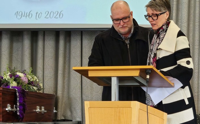 Two people standing at a lectern at a funeral